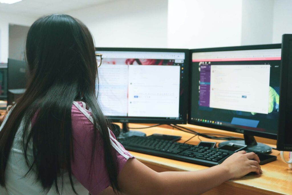 A girl browsing on her computer with two monitors